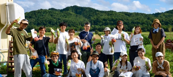 農作物を手にした地域事業の参加者集合写真